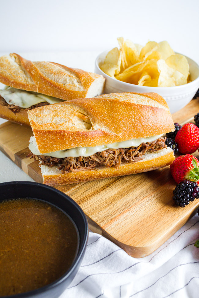 Slow cooker French Dip Sandwiches on a wooden cutting board.