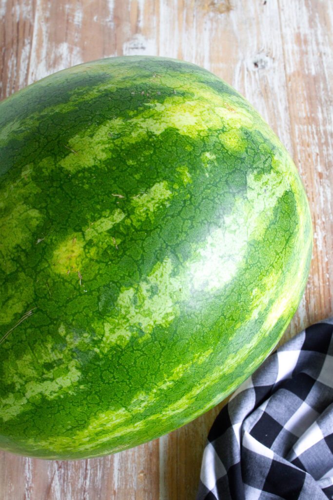 A whole ripe watermelon on a wooden table.