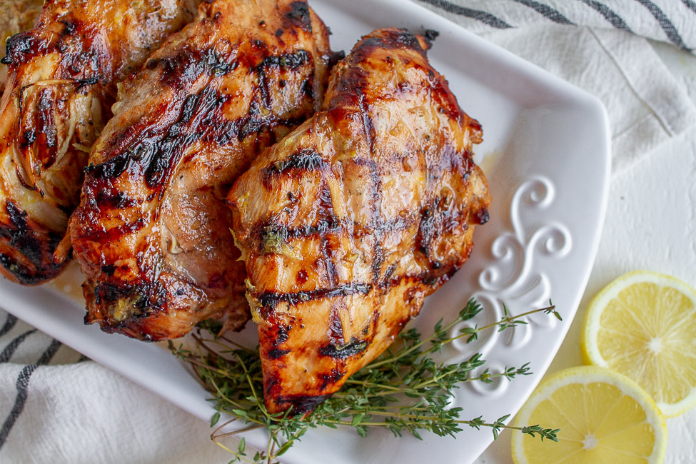 Grilled Lemon Chicken on a white plate with sprigs of thyme.
