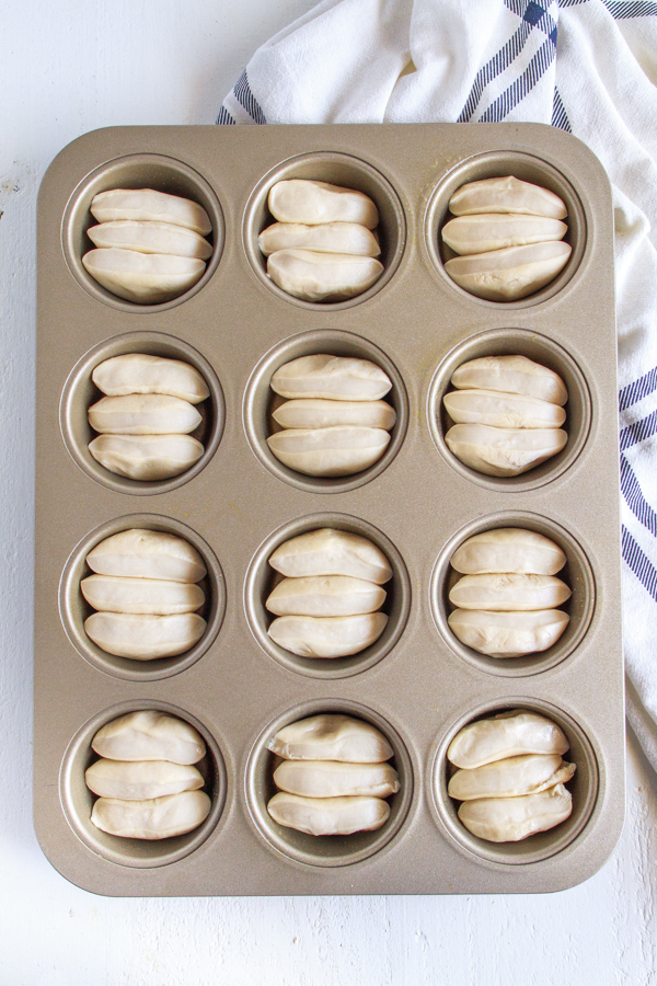 Bread rolls rising in a muffin pan.