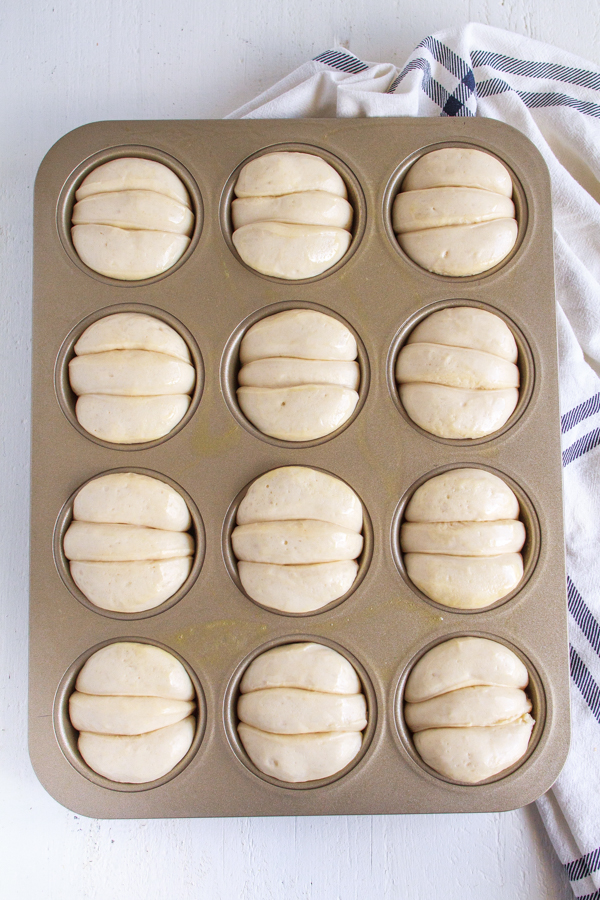 Risen bread rolls in a muffin tin.