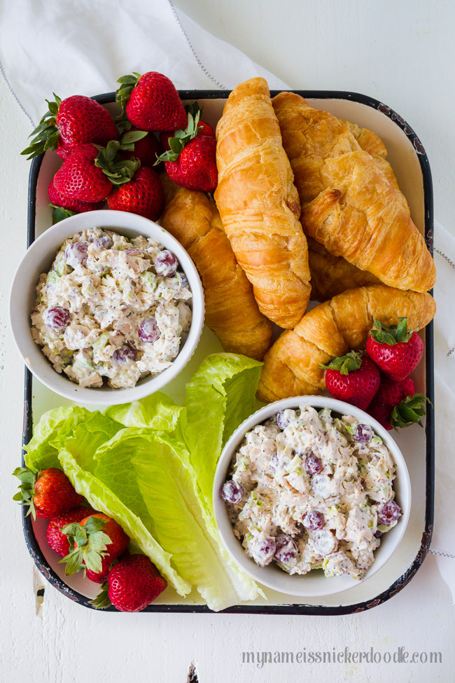 A tray filled with strawberries, croissants and chicken salad.