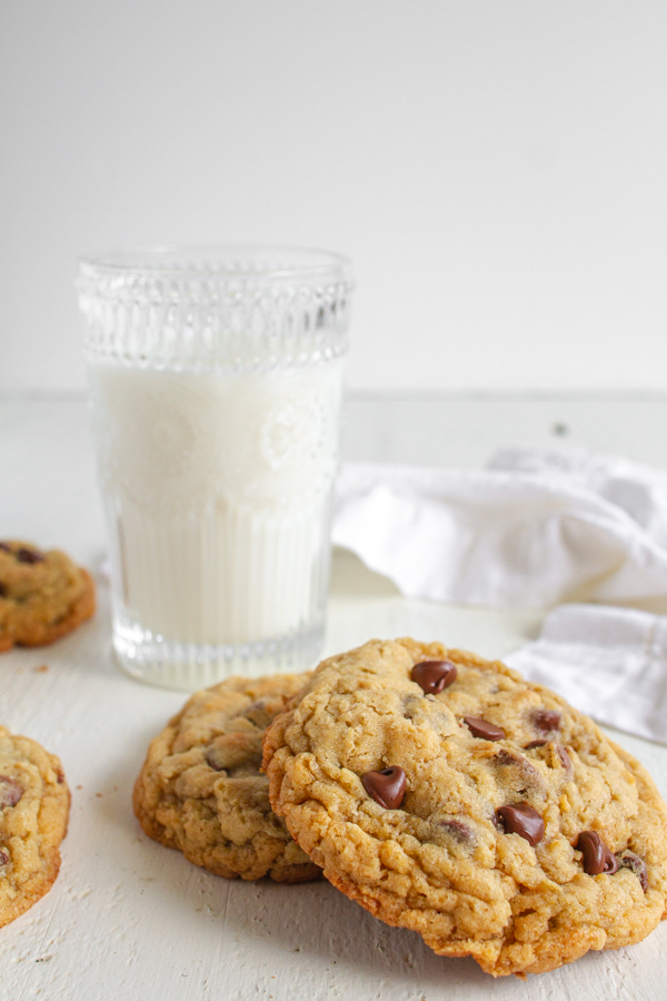 A glass of milk with two chocolate chip oatmeal cookies.