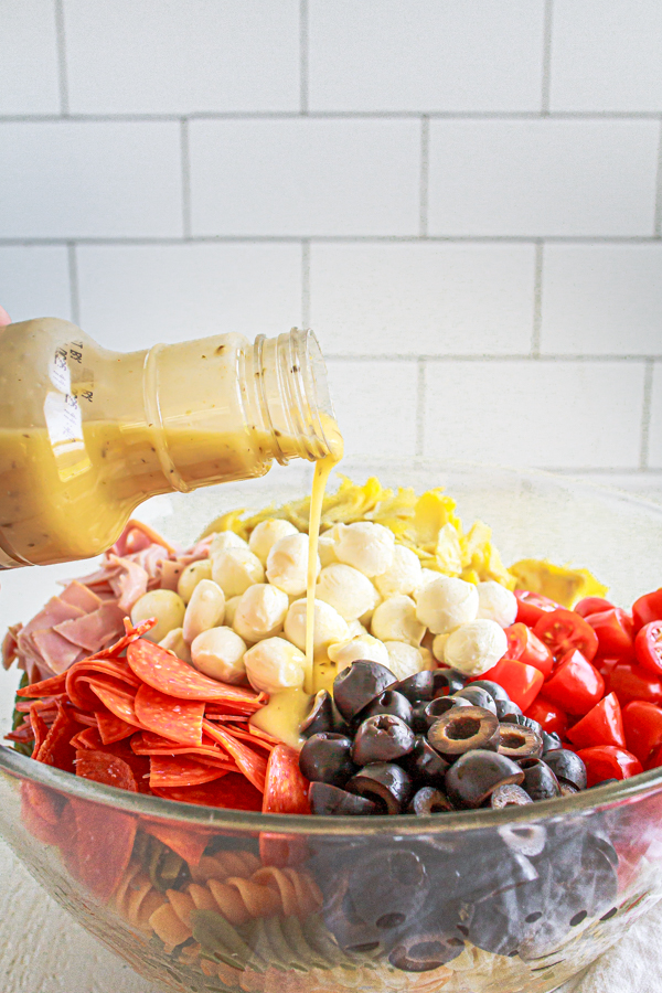 Pouring Italian Dressing over a pasta salad