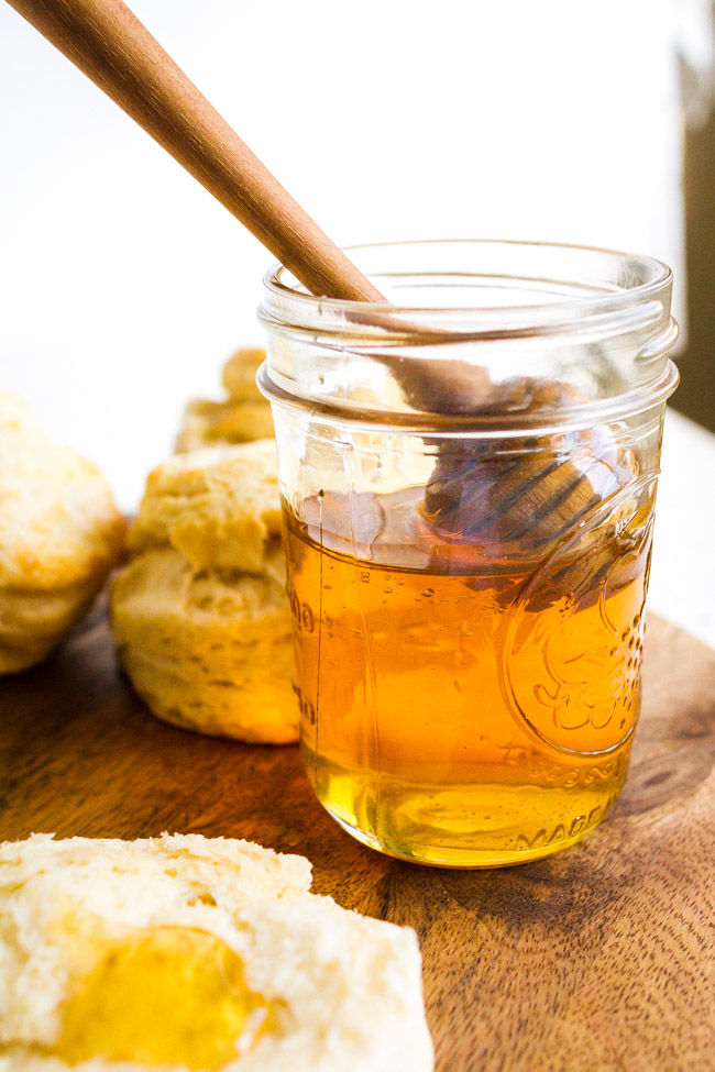 Jar of honey with a flaky biscuits.