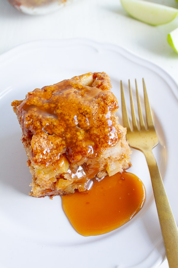 A slice of Caramel Apple Cake on a white plate with a gold fork.