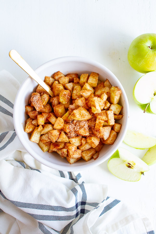 A bowl of chopped apples sprinkled with cinnamon and sugar.