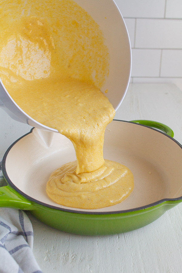 Cornbread batter being poured into a skillet