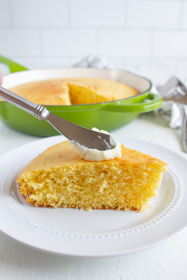 A slice of corn bread slathered with butter.