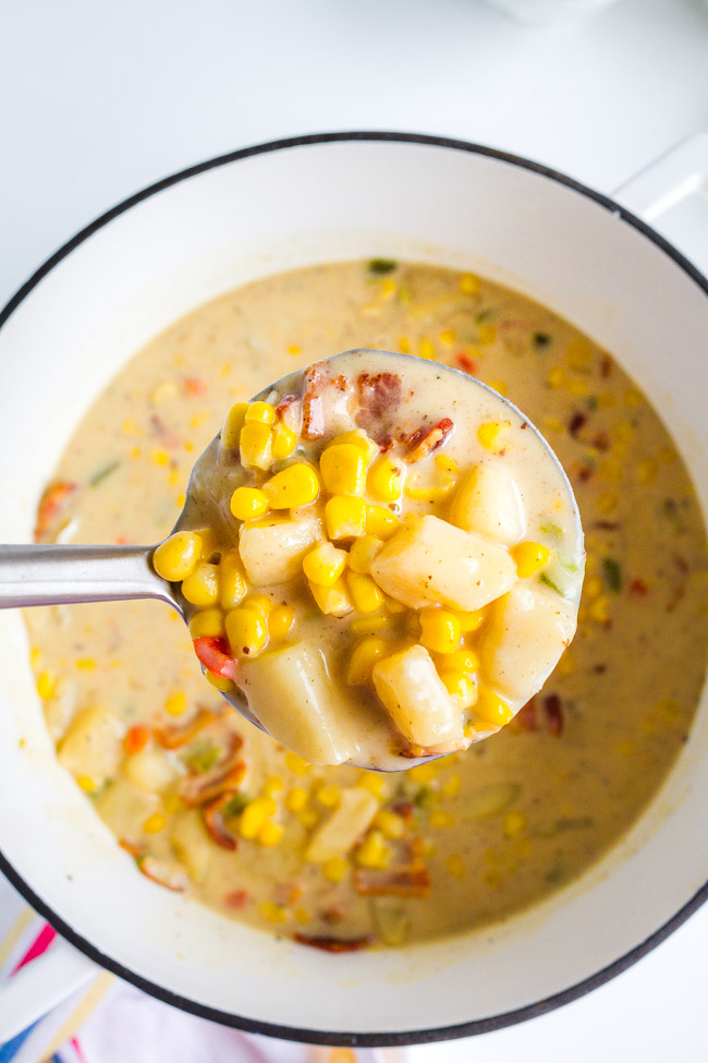 A white ceramic pot full of corn and potato soup.