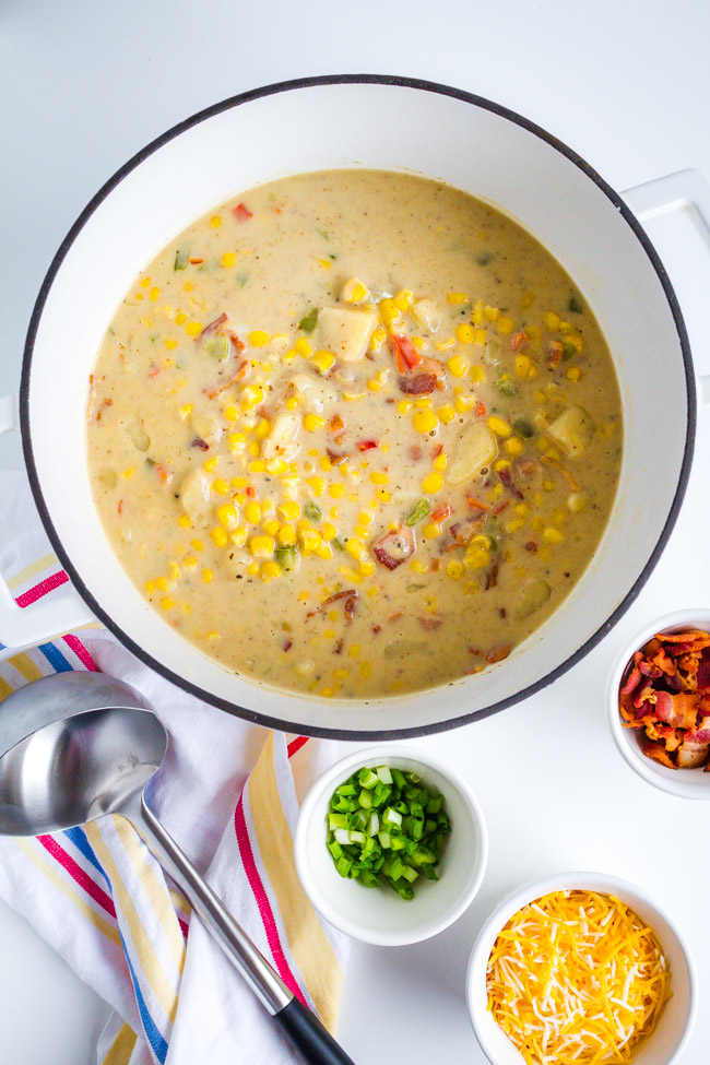 A white ceramic pot full of corn chowder.