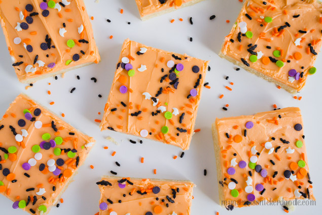 Easy Sugar Cookie Bars recipe with orange frosting and halloween sprinkles.