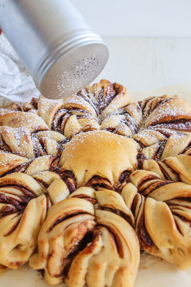 Chocolate Star Bread being sprinkled with powdered sugar.