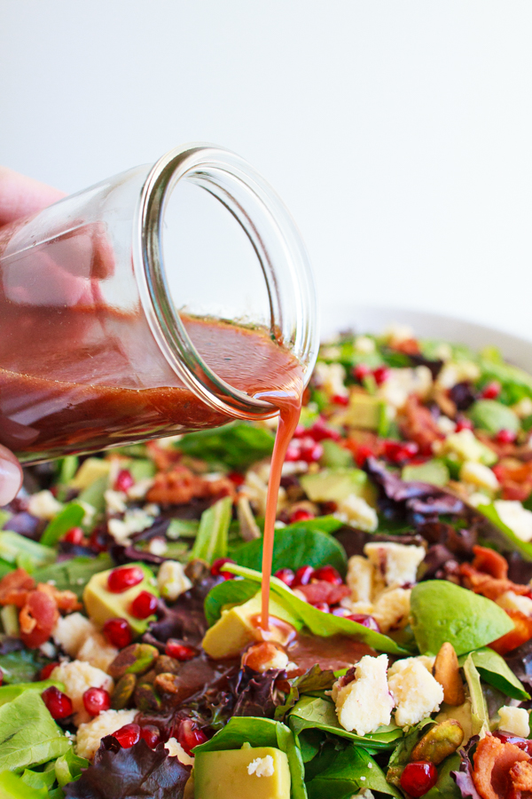 Pomegranate Salad Dressing being poured over a salad.