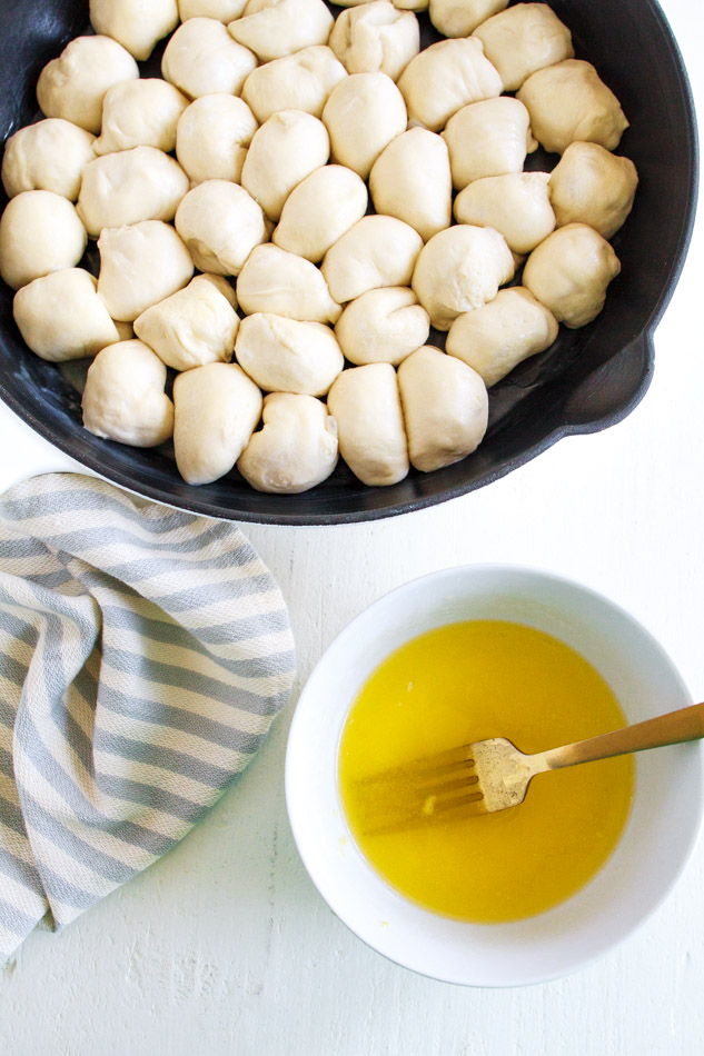 Roll dough balls in a skillet with a bowl of butter