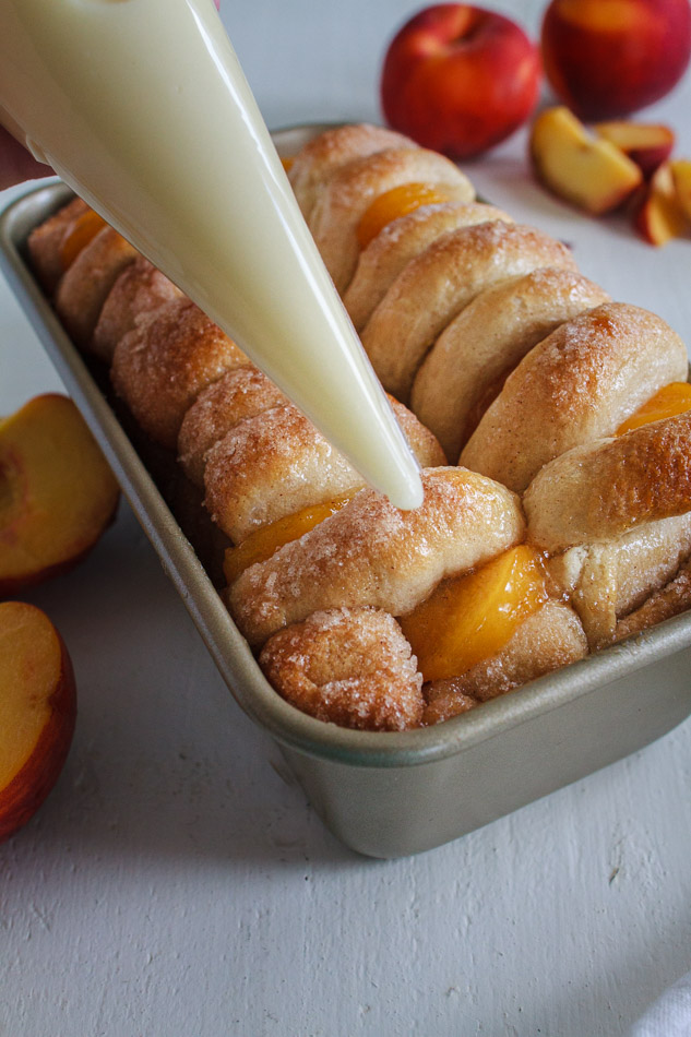 Peaches and Cream Pull Apart Bread with Cream Cheese Glaze in a loaf pan.