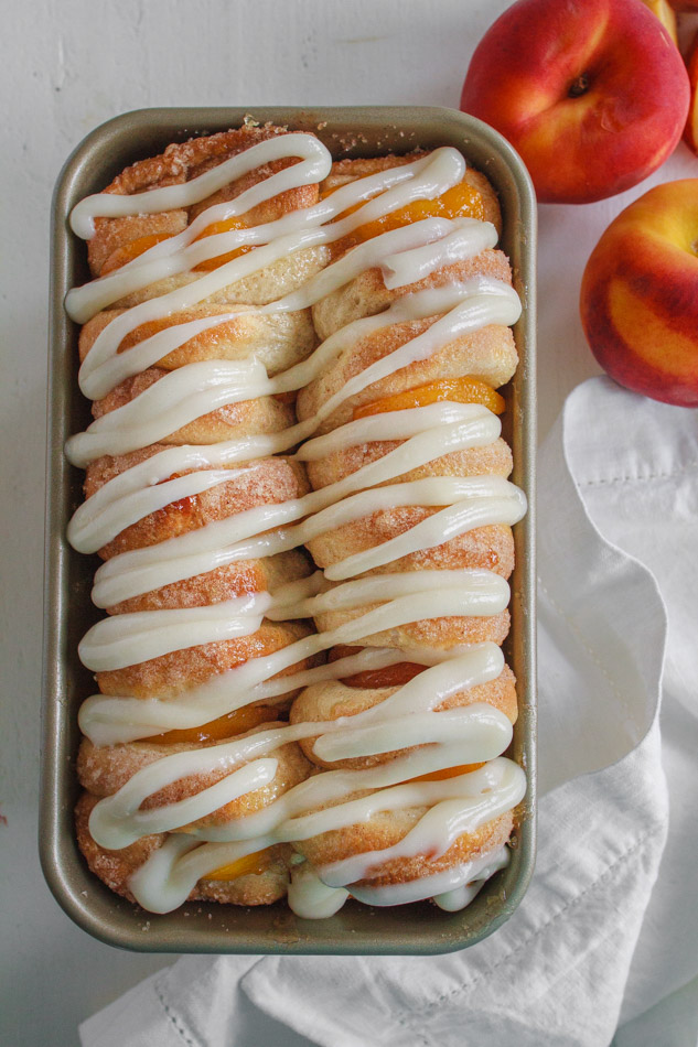 Peaches and Cream Pull Apart Bread with Cream Cheese Glaze in a loaf pan.