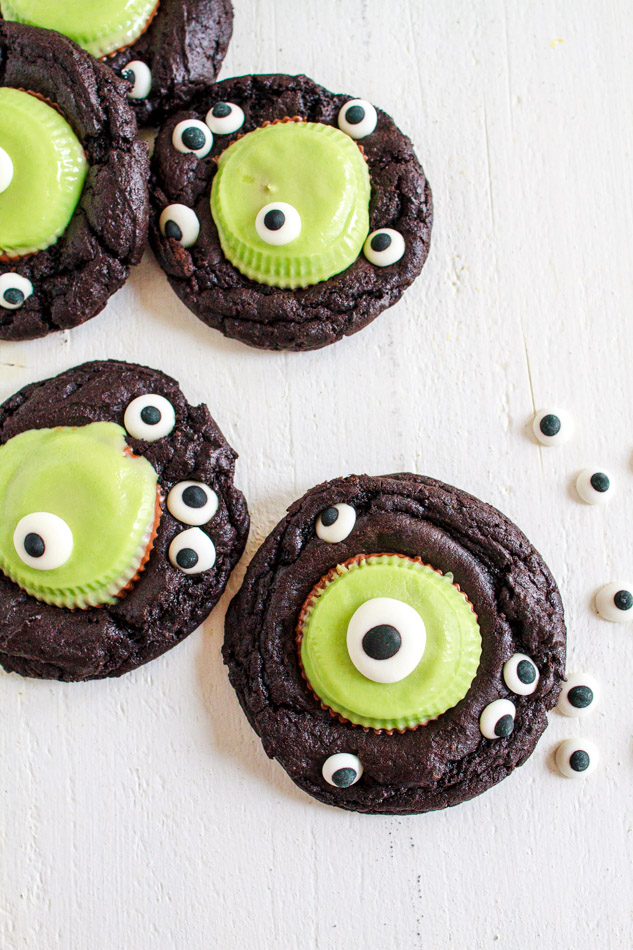 Halloween Monster Cookies are a fun and spooky treat.  Fudgey cookies full of chocolate flavor and black coco powder.  They are then embellished with Googley Candy Eyes and finished off with a Reese's Peanut Butter Franken Cup.  