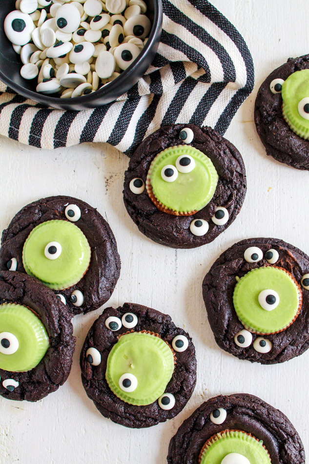 Halloween Monster Cookies are a fun and spooky treat.  Fudgey cookies full of chocolate flavor and black coco powder.  They are then embellished with Googley Candy Eyes and finished off with a Reese's Peanut Butter Franken Cup.  
