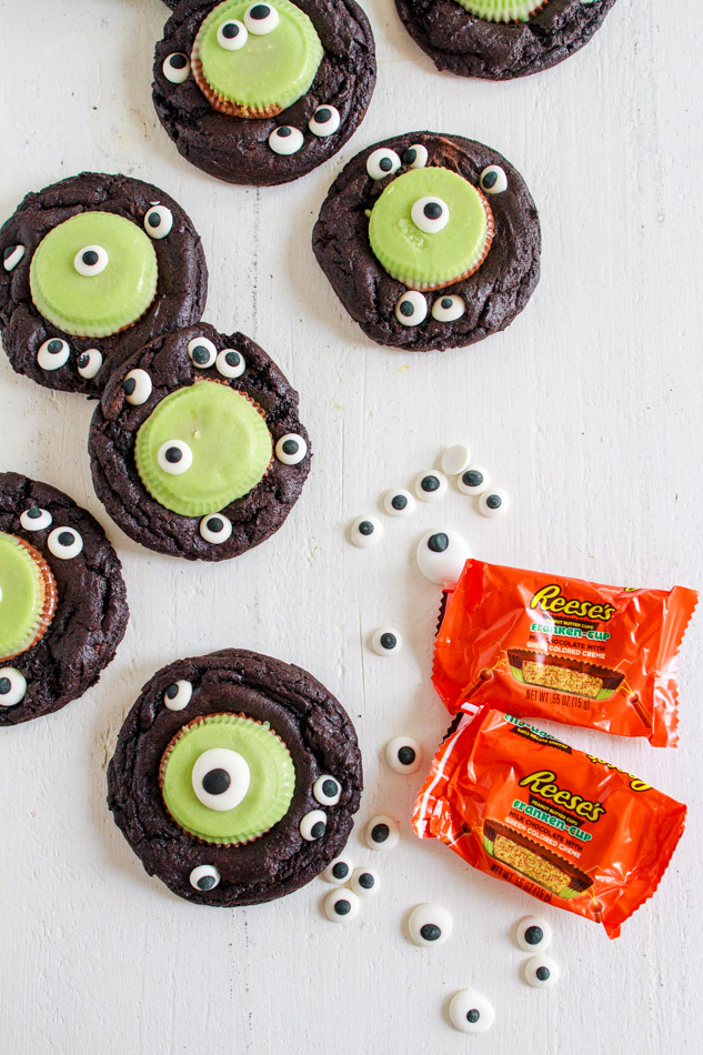 Halloween Monster Cookies are a fun and spooky treat.  Fudgey cookies full of chocolate flavor and black coco powder.  They are then embellished with Googley Candy Eyes and finished off with a Reese's Peanut Butter Franken Cup.  